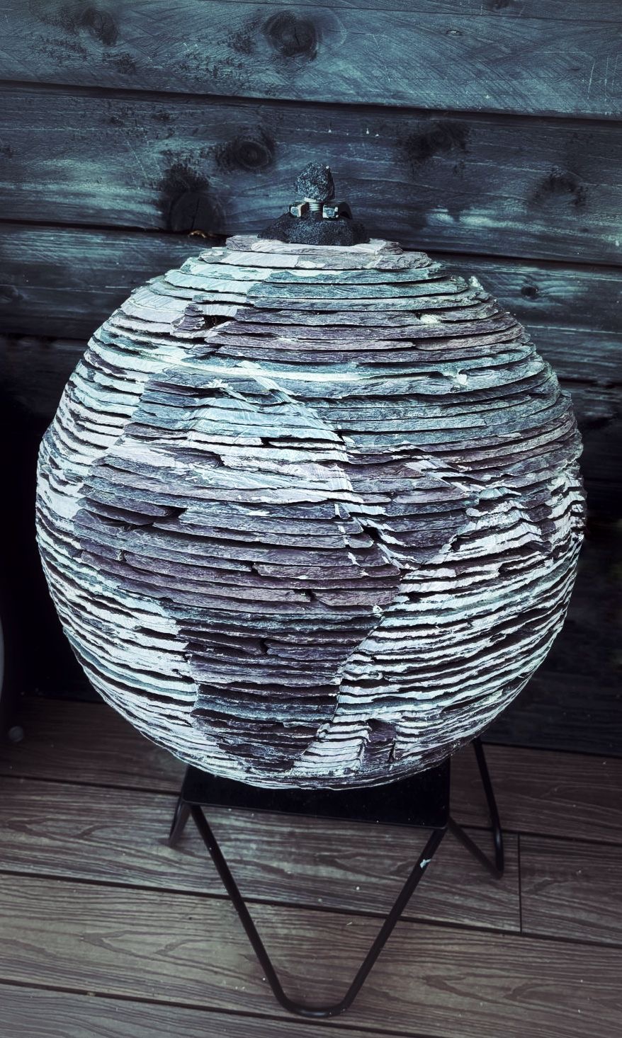 Sculptural globe made from layered slate on a black metal stand